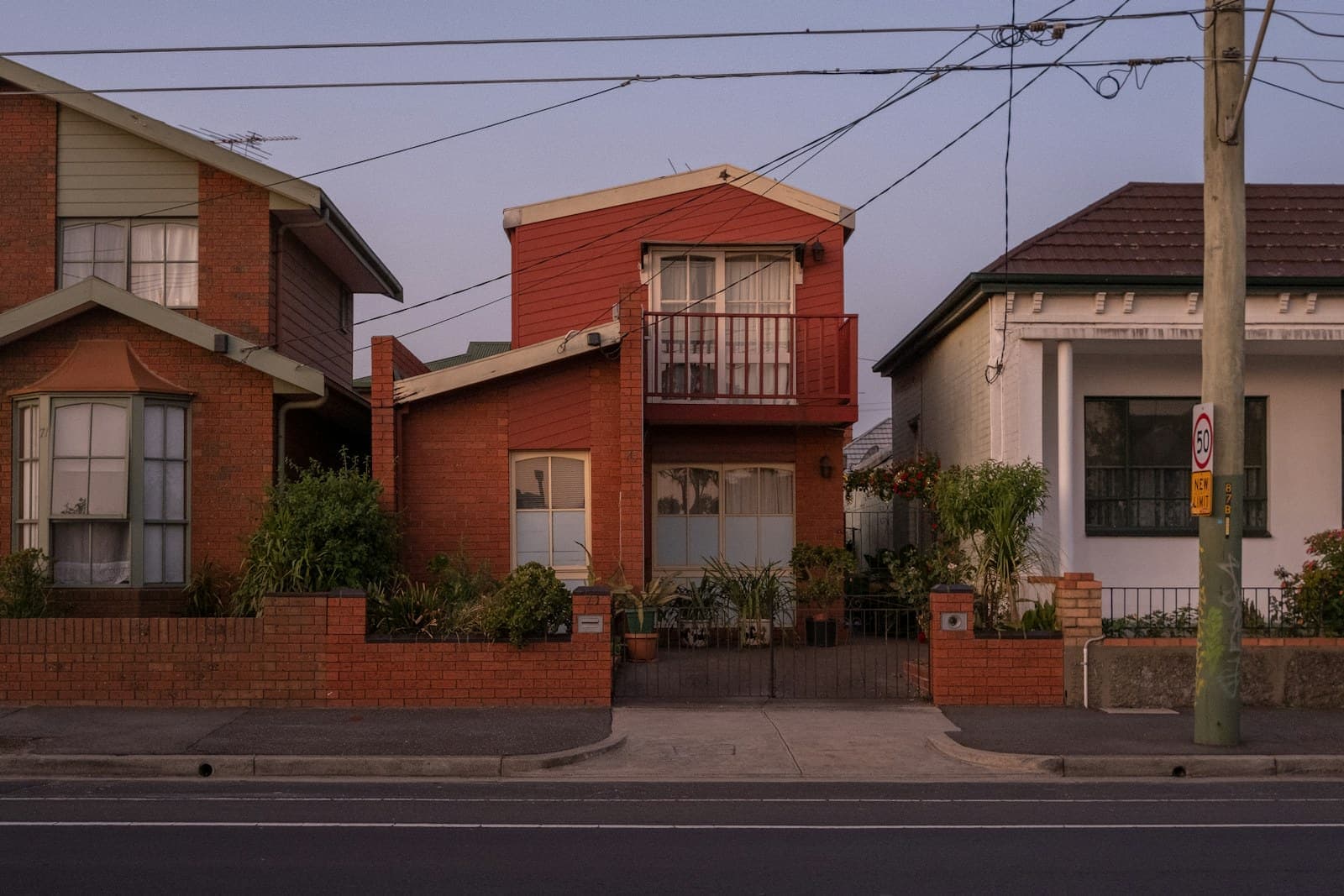 Two-storey brick terrace with a first-floor balcony on a quiet street